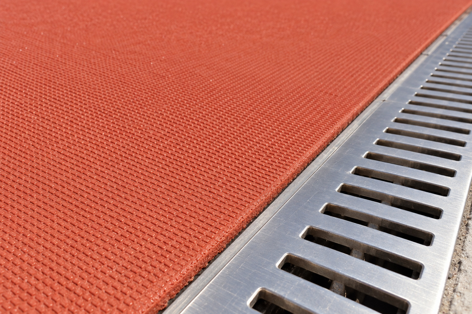 Flush termination between a prefabricated rubber track and a linear drainage channel