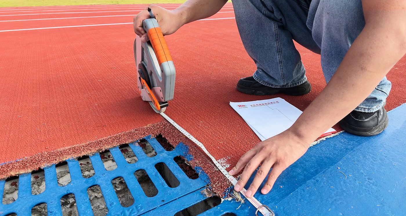 Tape measure positioned along a track edge beside a drainage channel