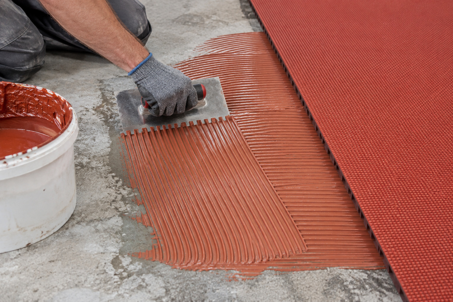 Uniform adhesive ridges formed with a notched trowel on a prepared foundation
